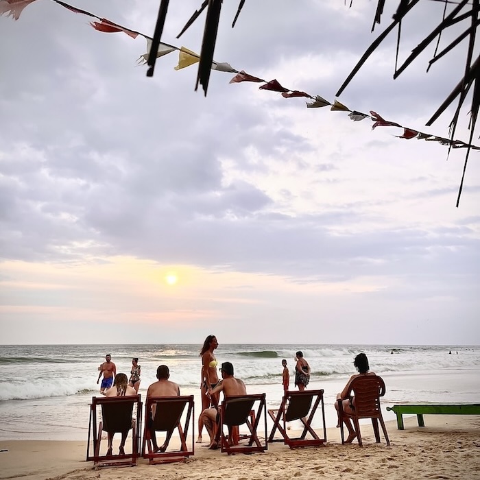 People relaxing in beach hammocks while watching the sunset in Sri Lanka.