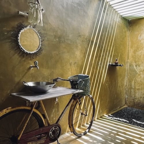 Open-air garden bathroom with recycled bicycle vanity at Kundala House